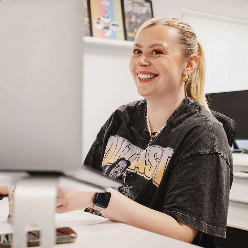 Smiling young woman working at a desk with computer