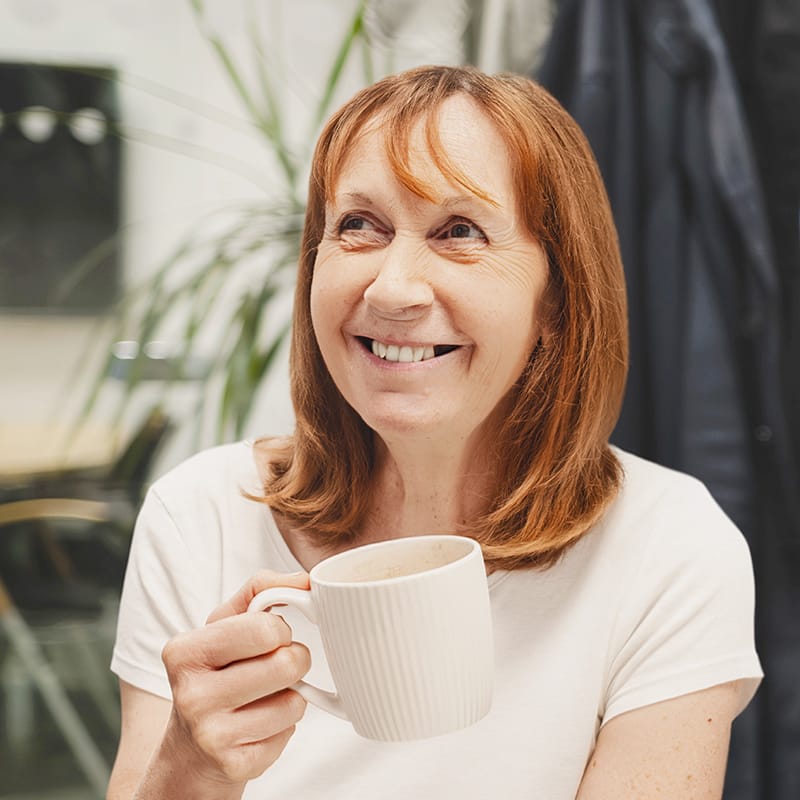 Smiling middle-aged woman holding a white ceramic mug