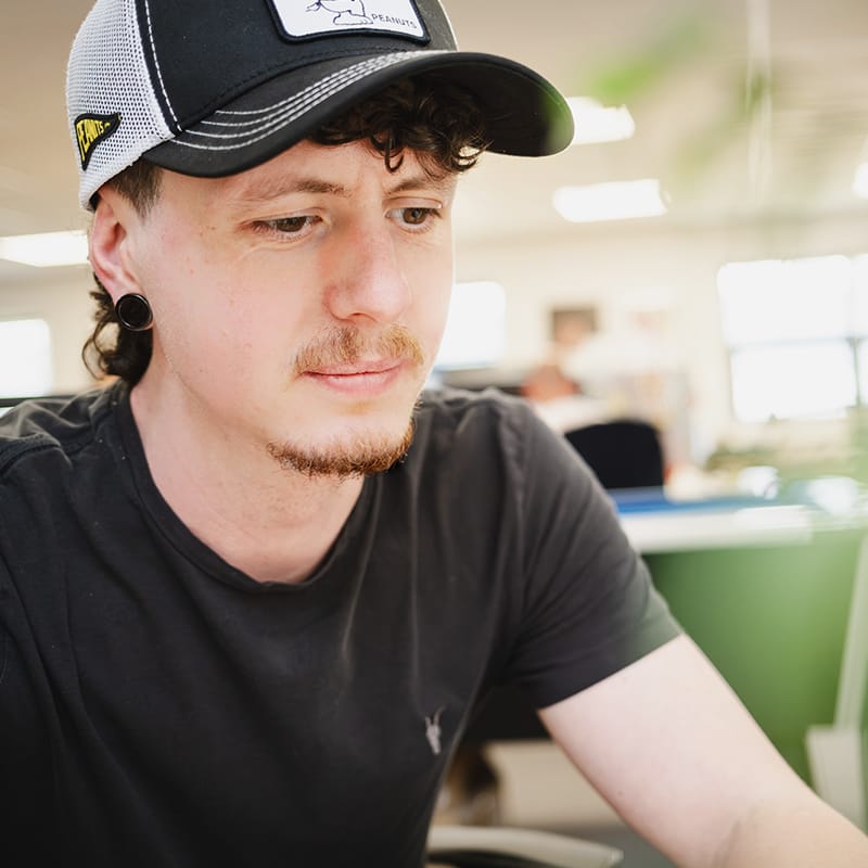 Young man wearing Peanuts cap working in office