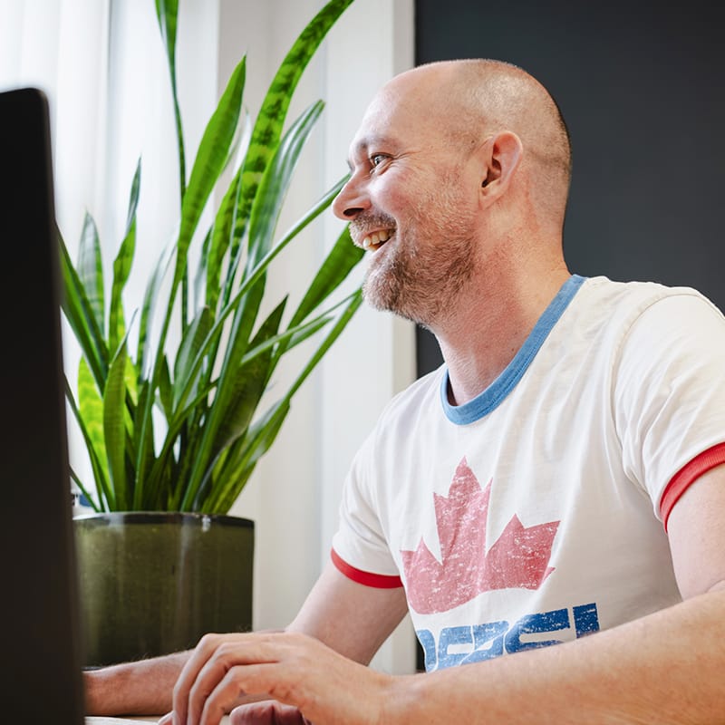 Smiling man working at computer wearing Canadian maple leaf t-shirt