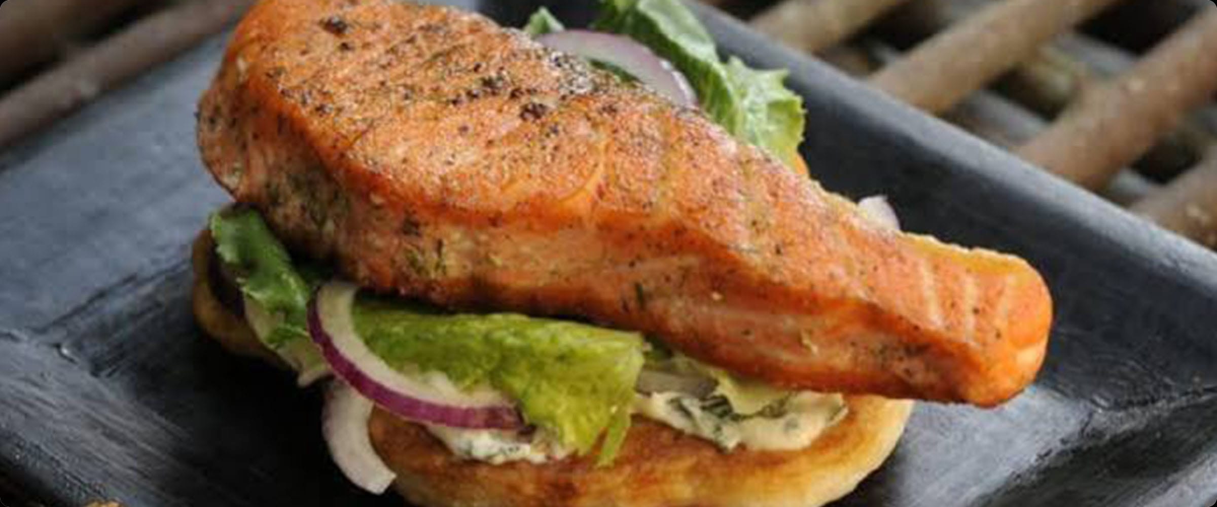 Grilled salmon burger with lettuce and red onion