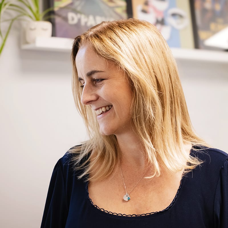 Smiling blonde woman in navy top in bright office