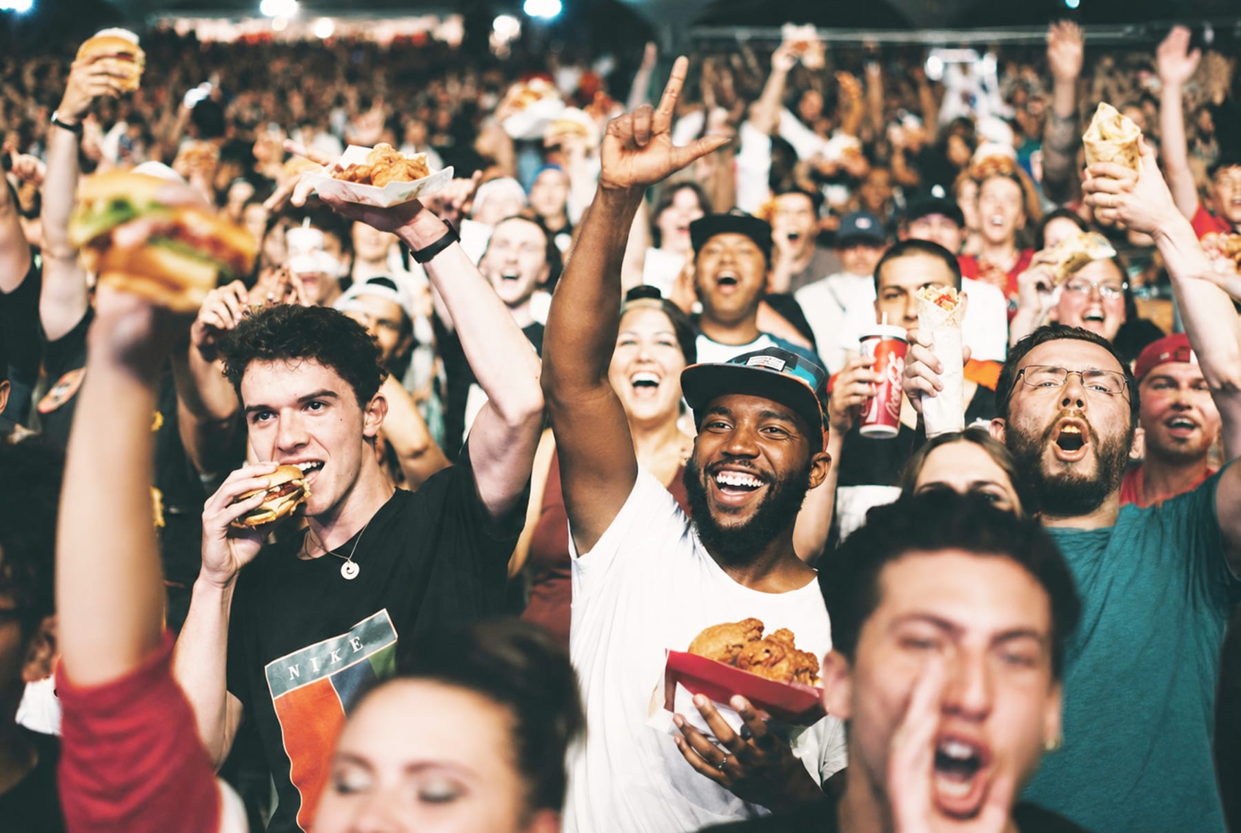 Excited festival crowd eating food and cheering at live event
